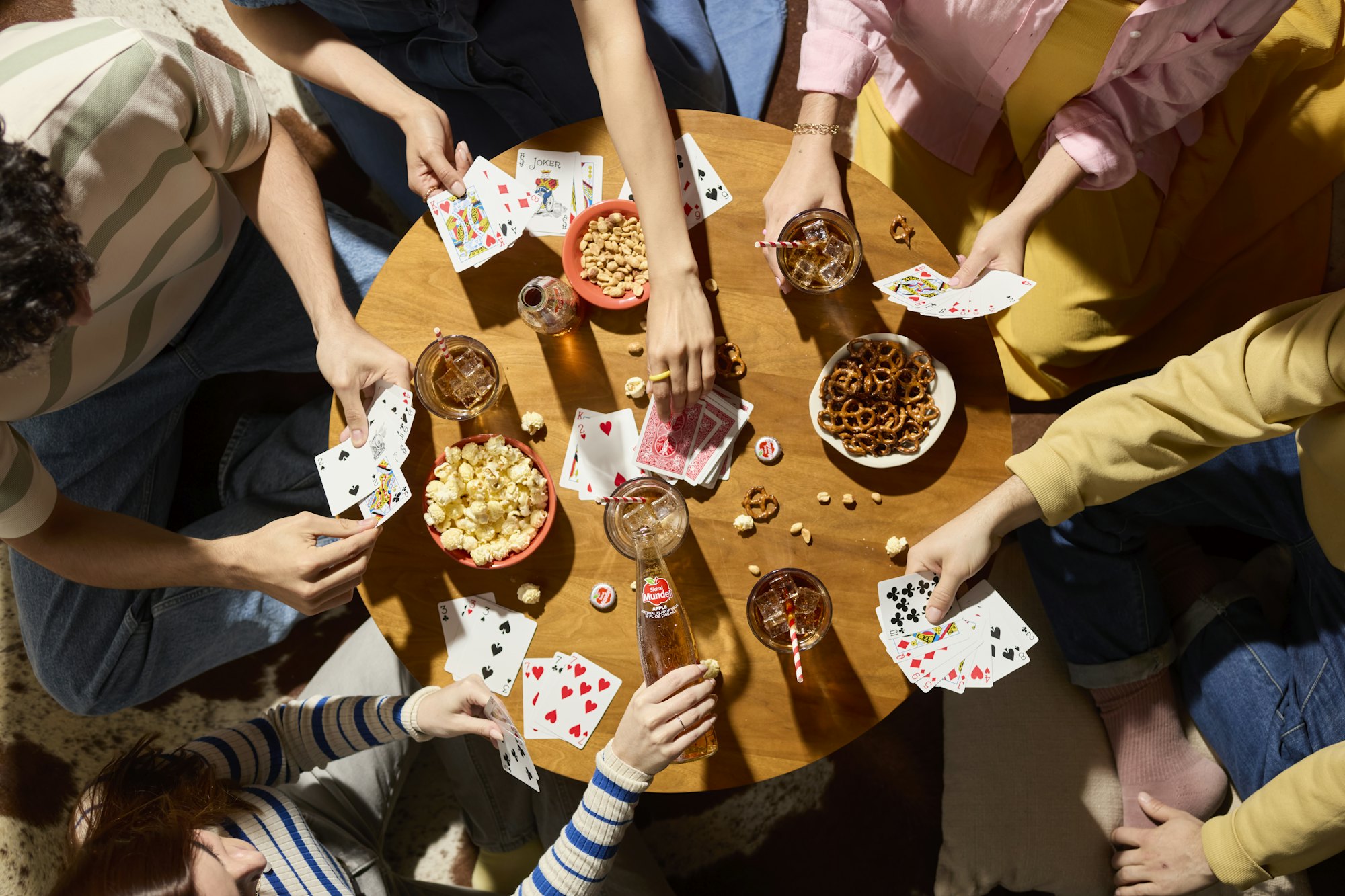 Friends playing cards around a table, seen from above