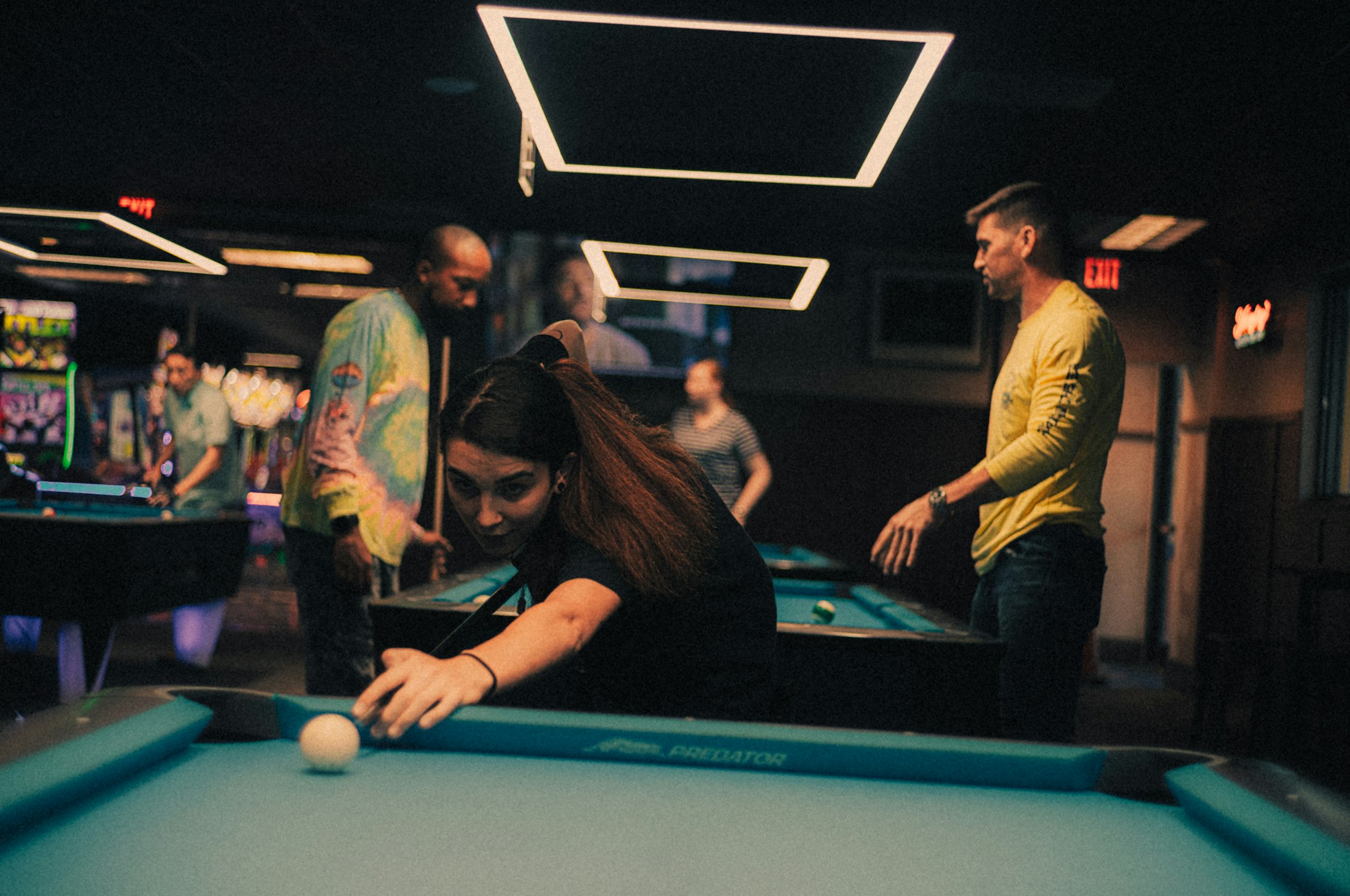 Friends playing pool in a dimly lit games bar